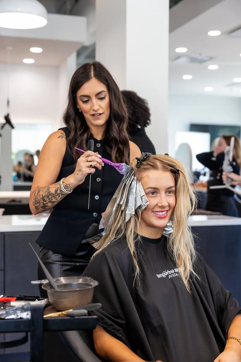 Stylist applying colour to a blonde client at Cuts-N-Stuff Salon &amp; Day Spa